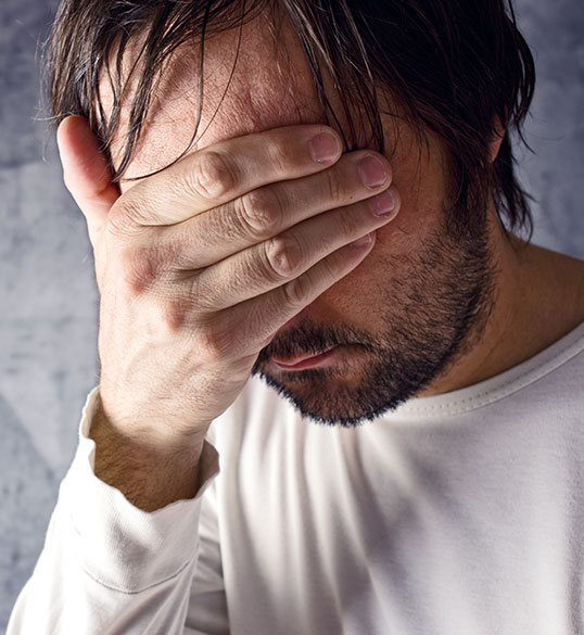 Man covering his face with one hand in shame