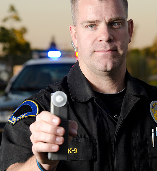 Police officer pointing a Breathalyzer tester