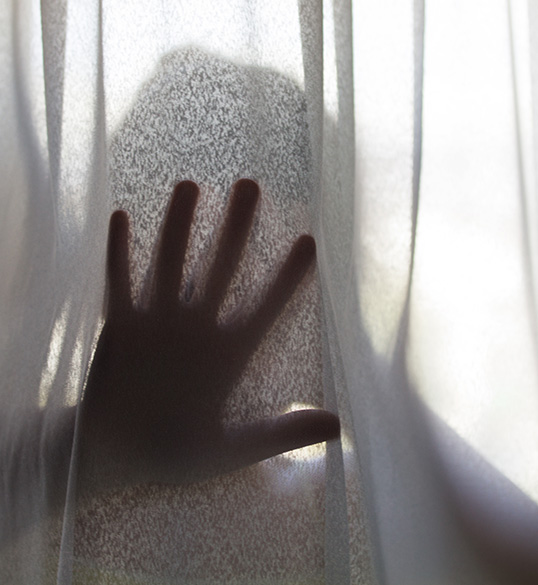 Person hiding behind curtains peeking out of hand